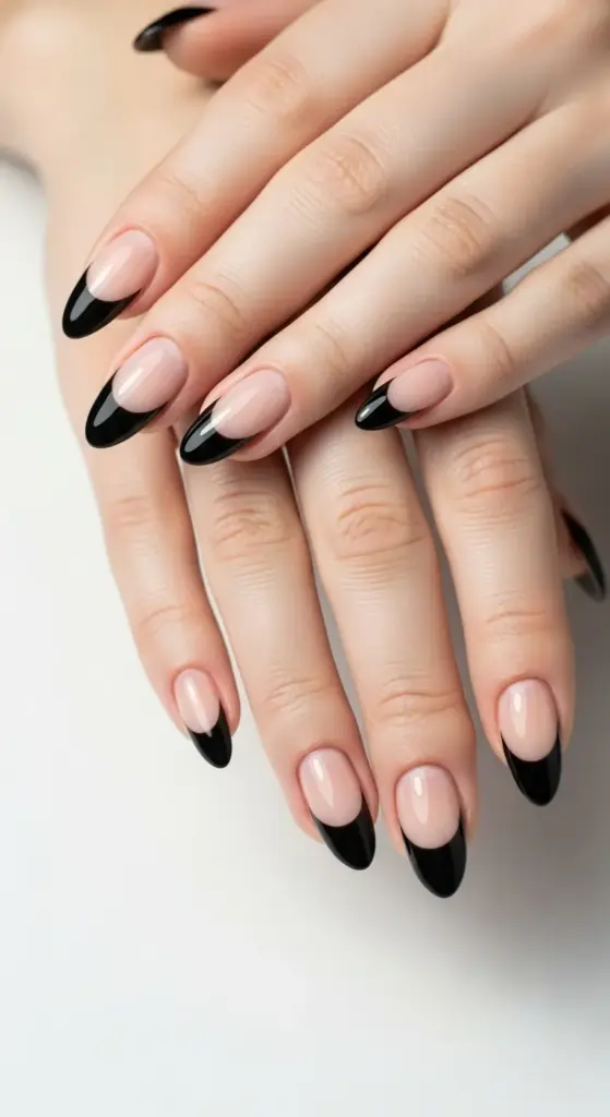 Classic and elegant hands with long, almond-shaped nails featuring glossy black french tip nails over a natural, clear base.